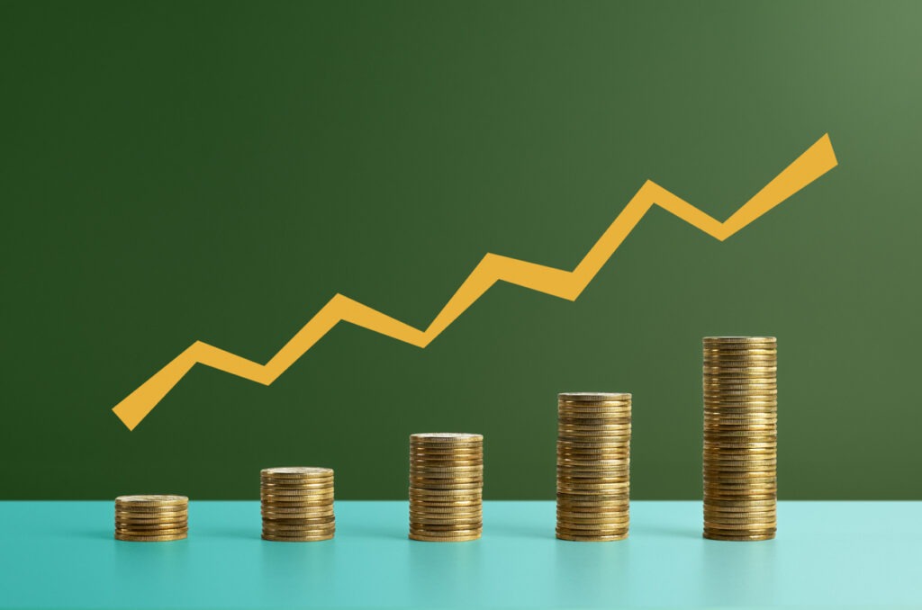 Five stacks of coins with a graph line above - stock photo. Coins arranged as a bar chart with a graph line above