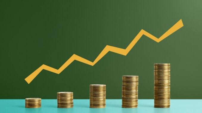 Five stacks of coins with a graph line above - stock photo. Coins arranged as a bar chart with a graph line above