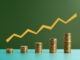 Five stacks of coins with a graph line above - stock photo. Coins arranged as a bar chart with a graph line above