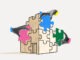 Several hands fit colorful puzzle pieces into the shape of a building on a light background. Concept of team collaboration, organizational development, integration and planning