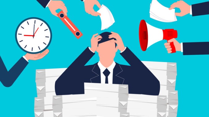 Heavy workload, overloaded with stress. Multi-tasking businessman sitting with his hands on his head in a file