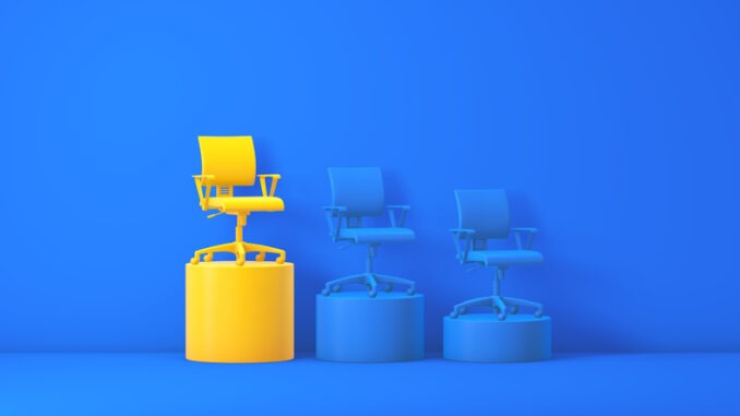 3D render: a yellow office chair stands on the tallest yellow podium in a blue studio, flanked by two lower blue chairs—bold contrast symbolizing leadership and career growth.