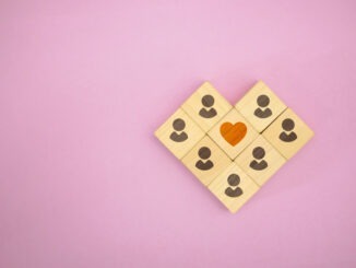 Wooden blocks forming people around a heart symbol, representing community, connection, love, and emotional support.