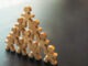 Wooden human figures forming a pyramid symbolizing teamwork, leadership, support, and organizational success. Concept of collaboration, unity, human resources, and business development.