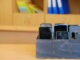 Students' cell phones are neatly organized in a wooden box on a desk, highlighting the policy of limited phone access during classes and promoting focus on learning