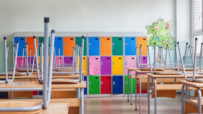 Modern emty classroom with colorful lockers and raised chairs on the tables