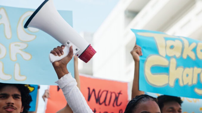 Strike, people and hands with megaphone in street for inflation, human rights or cost of living. Speaker, community and group in protest with bullhorn for rally, justice or higher wages for change