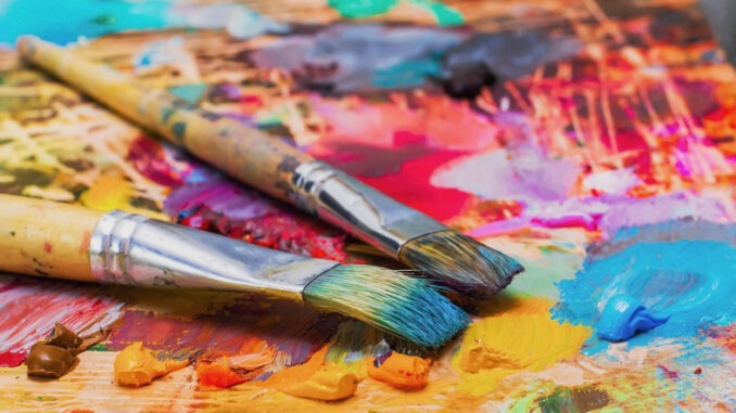 Used brushes on an artist's palette of colorful oil paint for drawing and painting