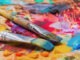 Used brushes on an artist's palette of colorful oil paint for drawing and painting