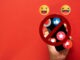 Concept of no social media interaction,Social Media Detox,Social Detoxification.,Hand holding a smartphone with crossed-out among social media notifications and emoji icons on red background.